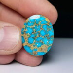 Nishapur turquoise cabochon in sky blue with a golden matrix web running across the face